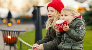 two girls sitting with one holding a mug