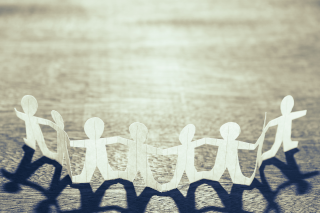 An image of paper doll cutouts holding hands
