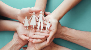 Hands holding a paper cutout of a family